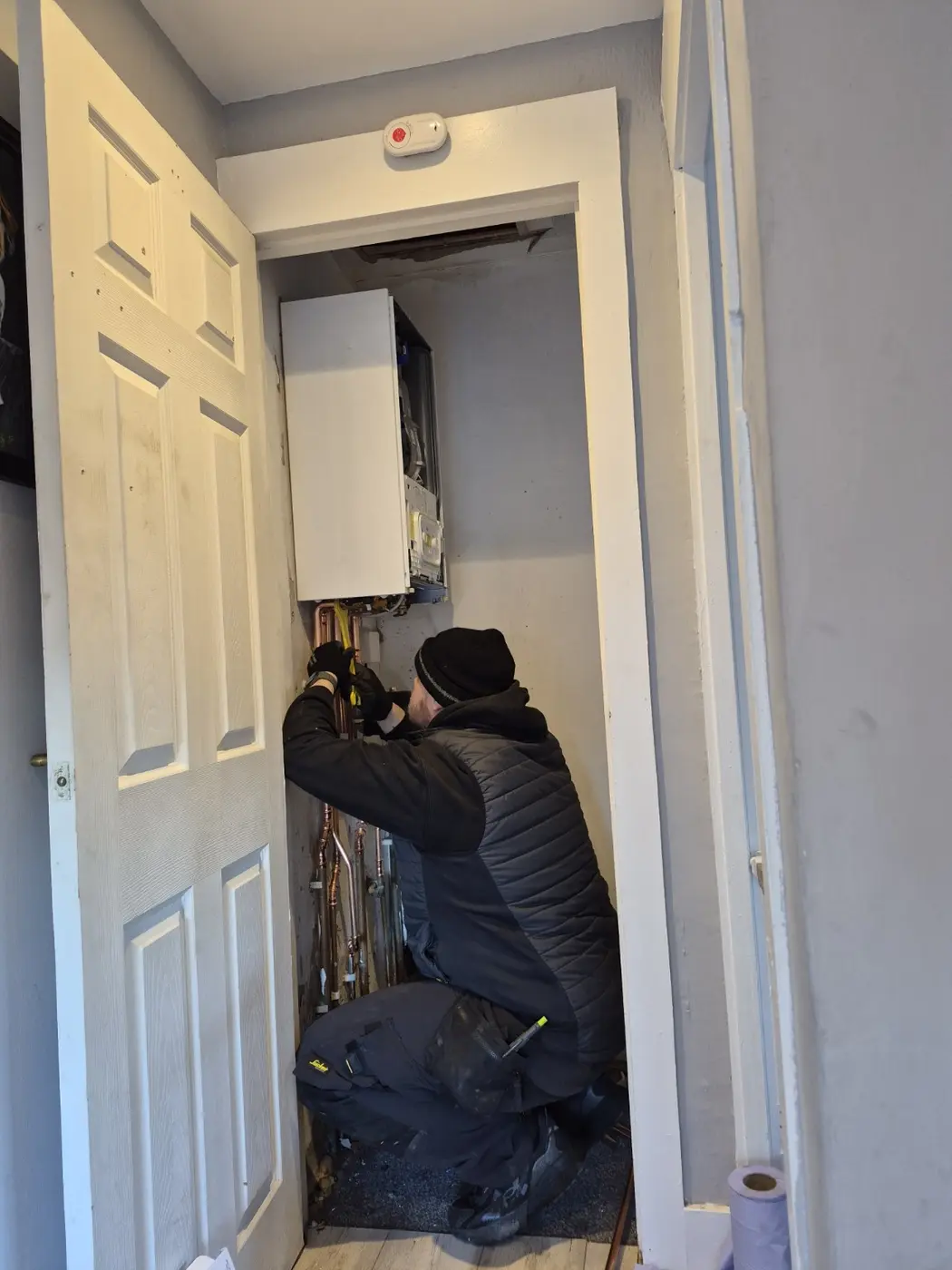 Craig working carefully beneath a wall mounted boiler